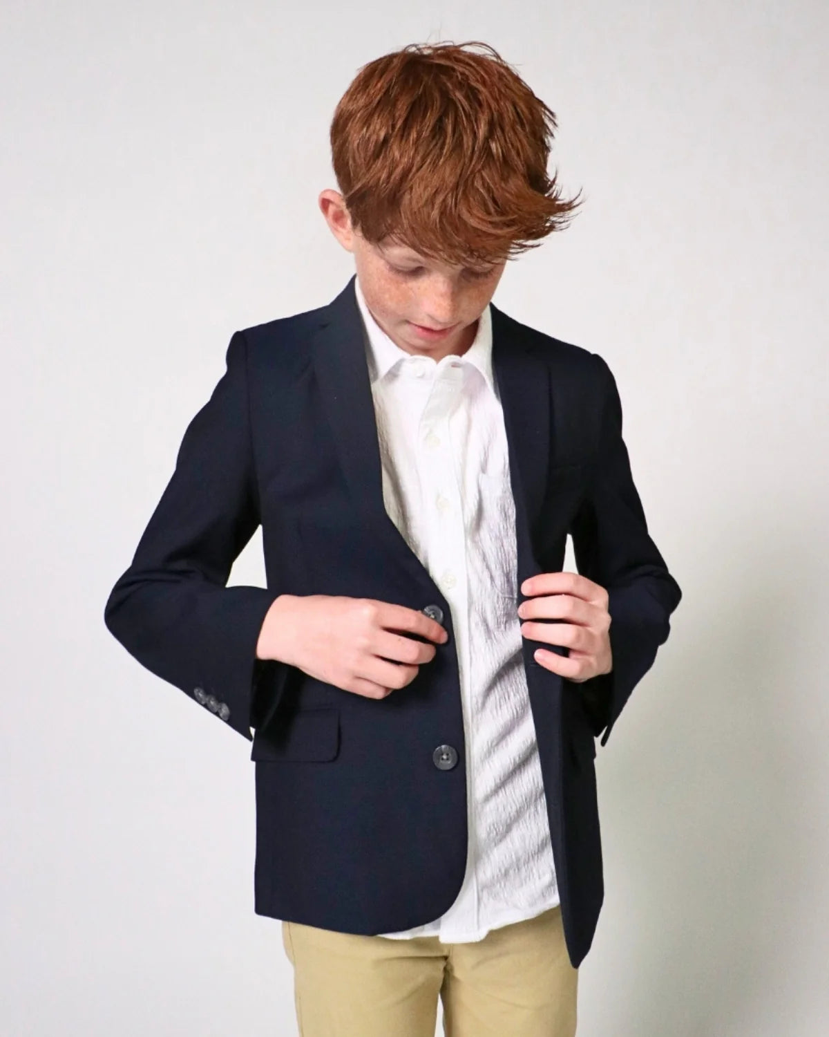 Person wearing a navy blazer over a white shirt with a light-colored background