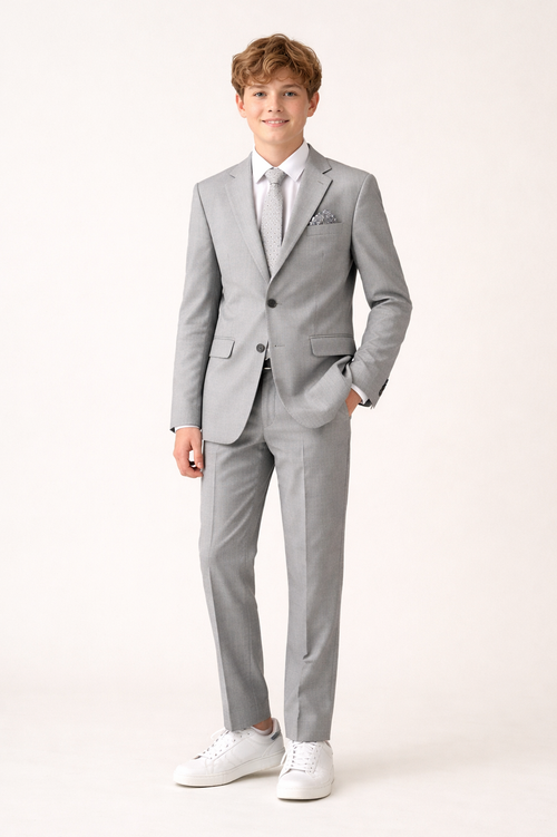 Young boy wearing a gray suit with a white shirt on a white background