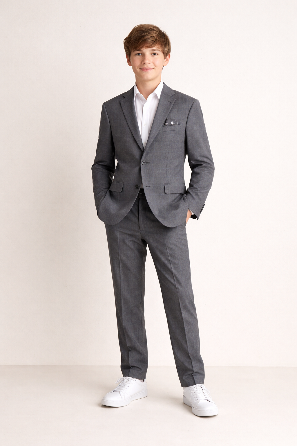 Person wearing a gray suit with a white shirt on a plain background