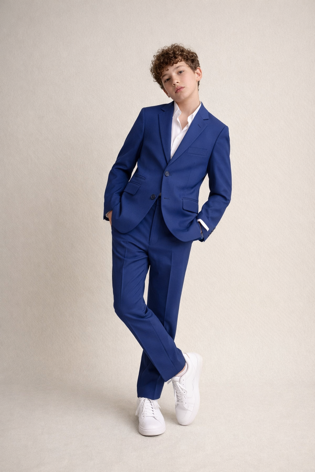 Person wearing a blue suit with white shoes on a beige background